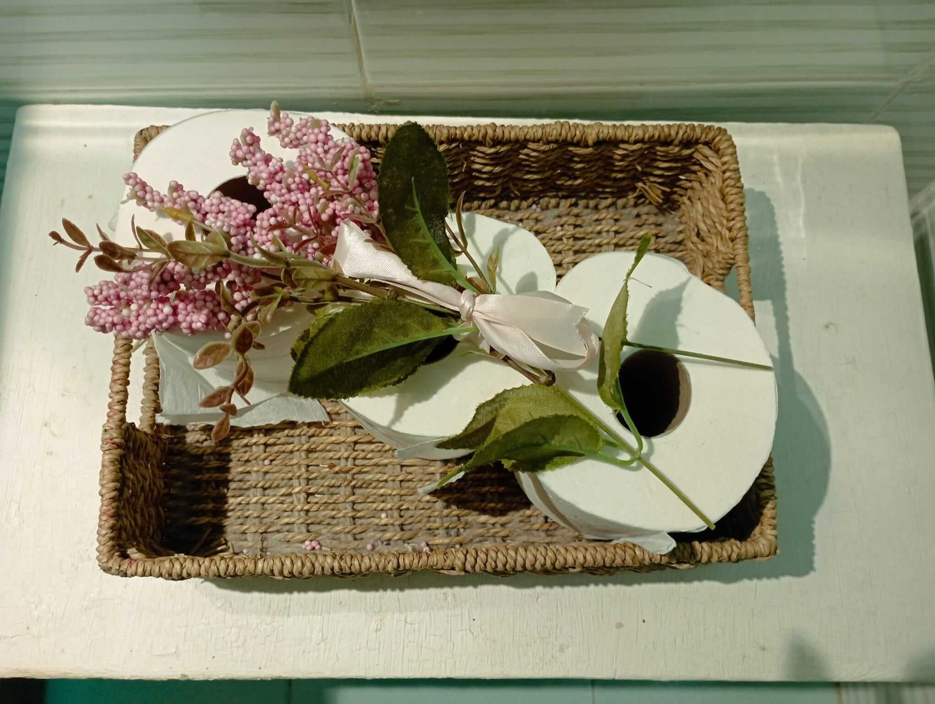 Una cesta de mimbre llena de papel higiénico y flores.