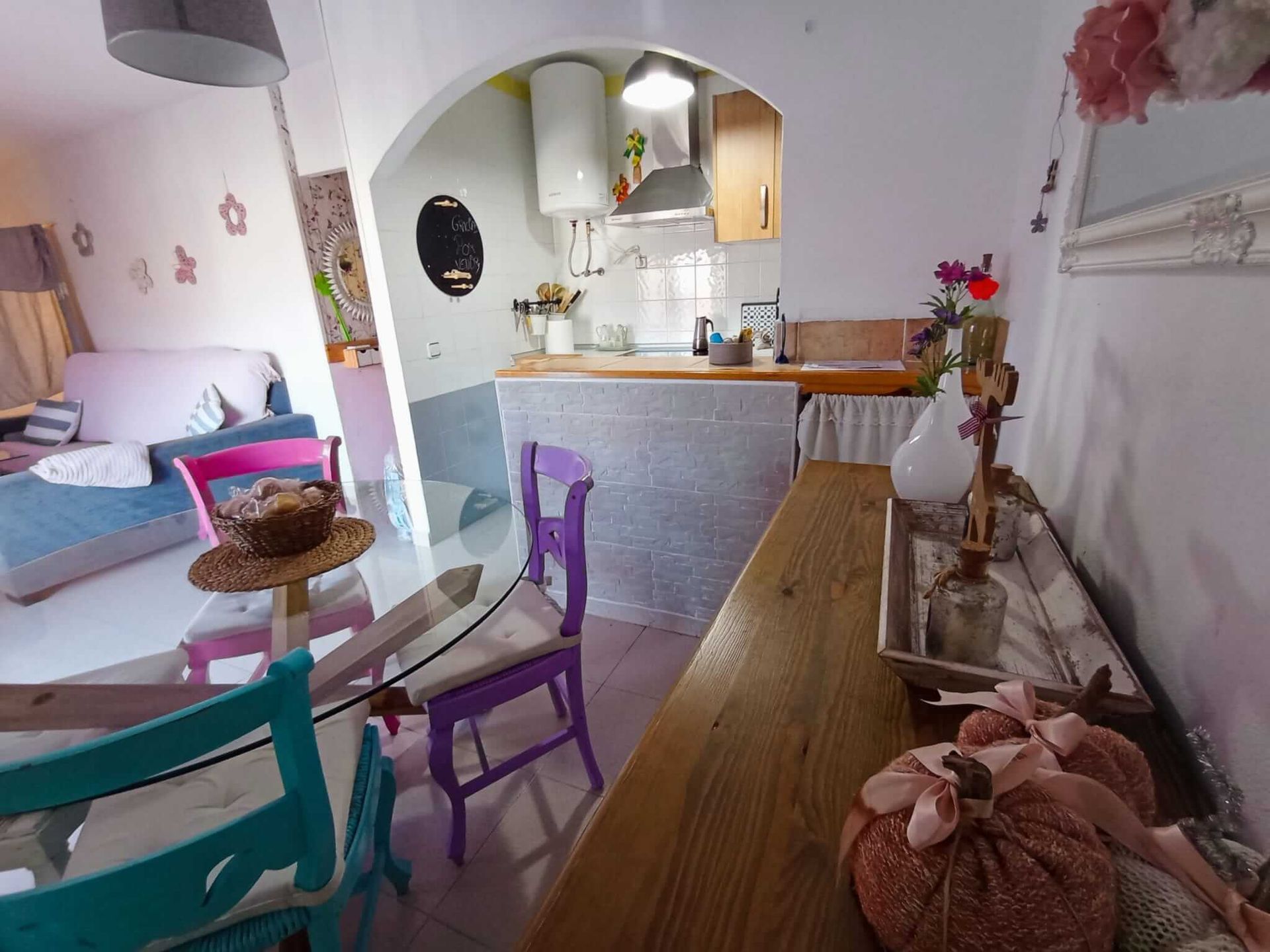 Una sala de estar con una mesa de cristal y sillas moradas.