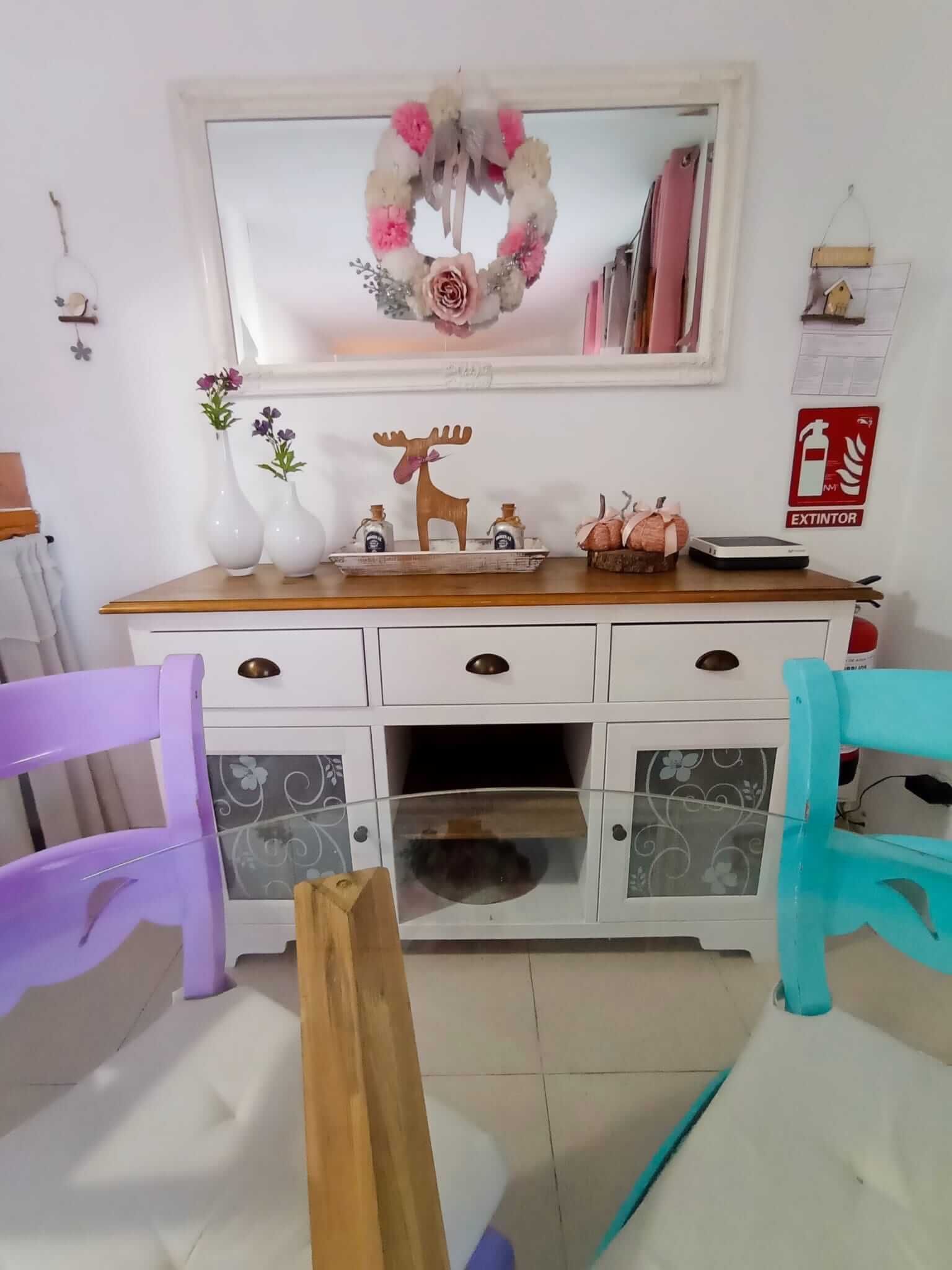 Una sala de estar con una cómoda blanca, sillas moradas y un espejo.