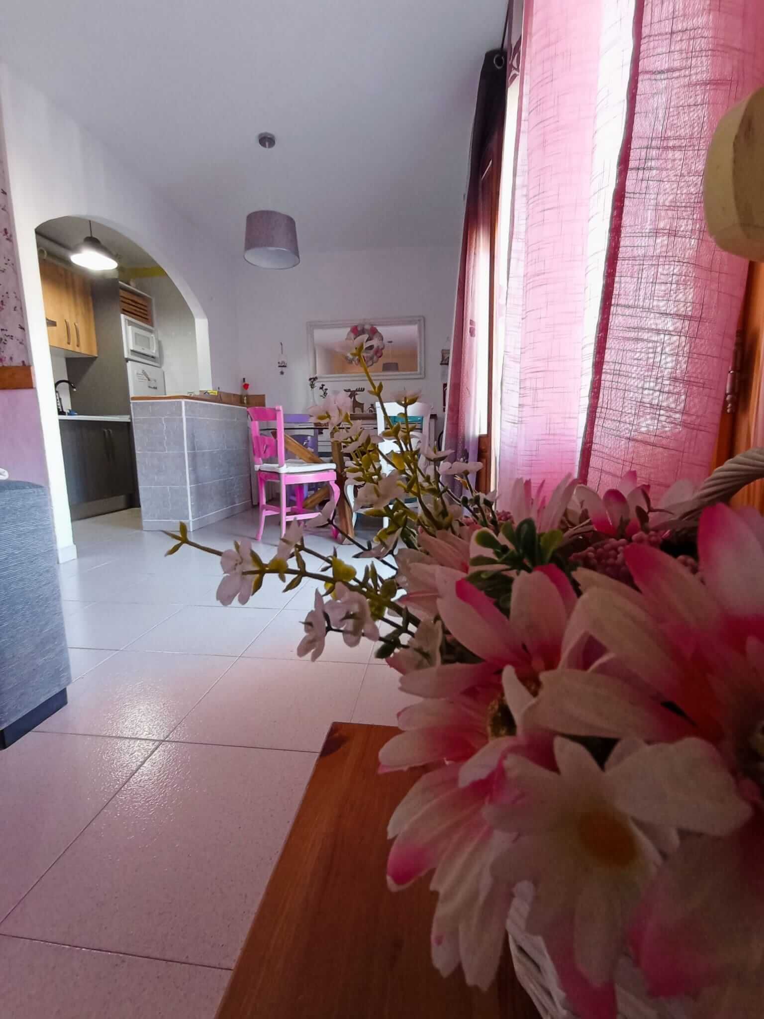 Un jarrón con flores rosas y blancas está sobre una mesa en una sala de estar.