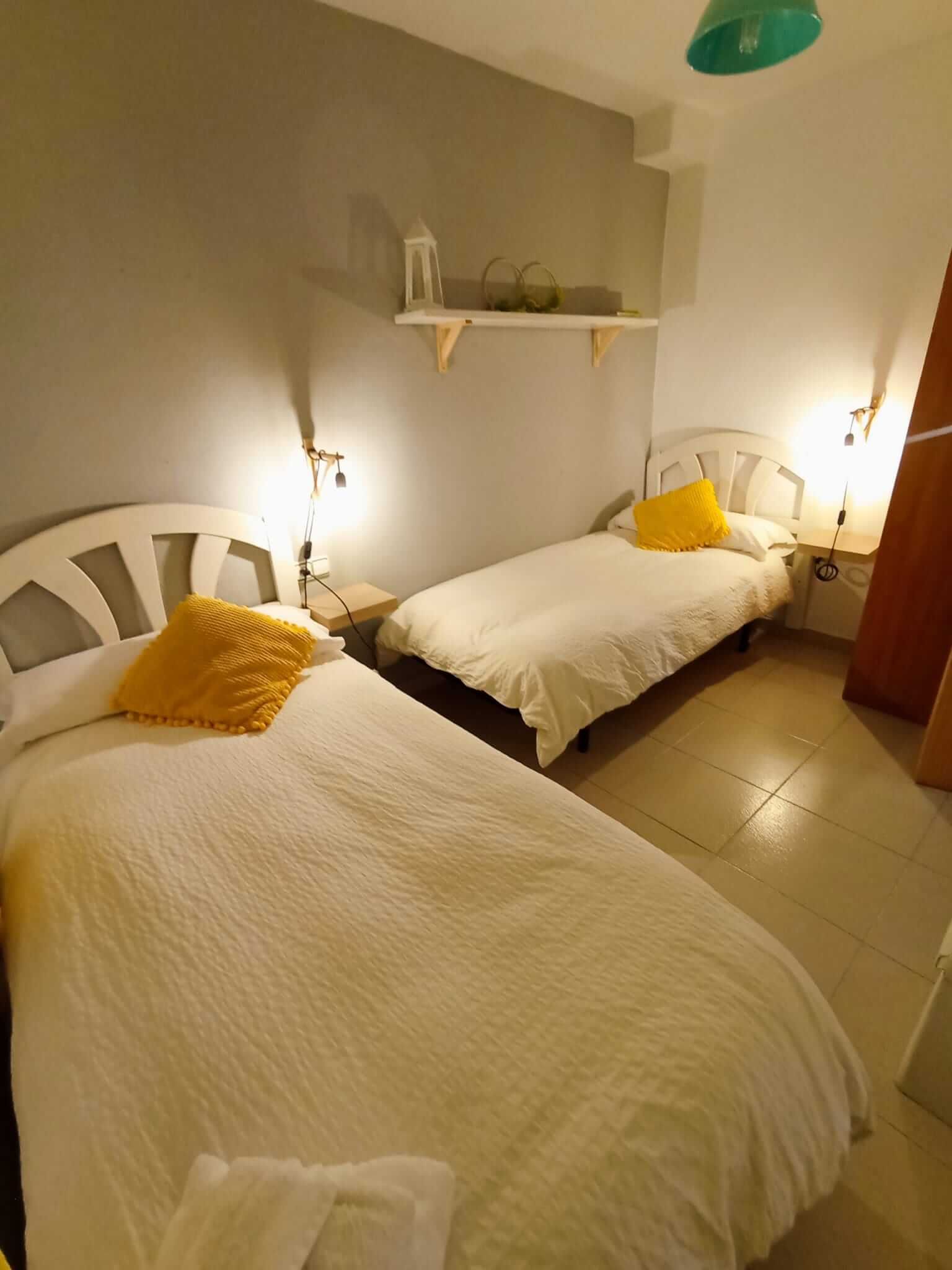 Un dormitorio con dos camas y un estante en la pared.