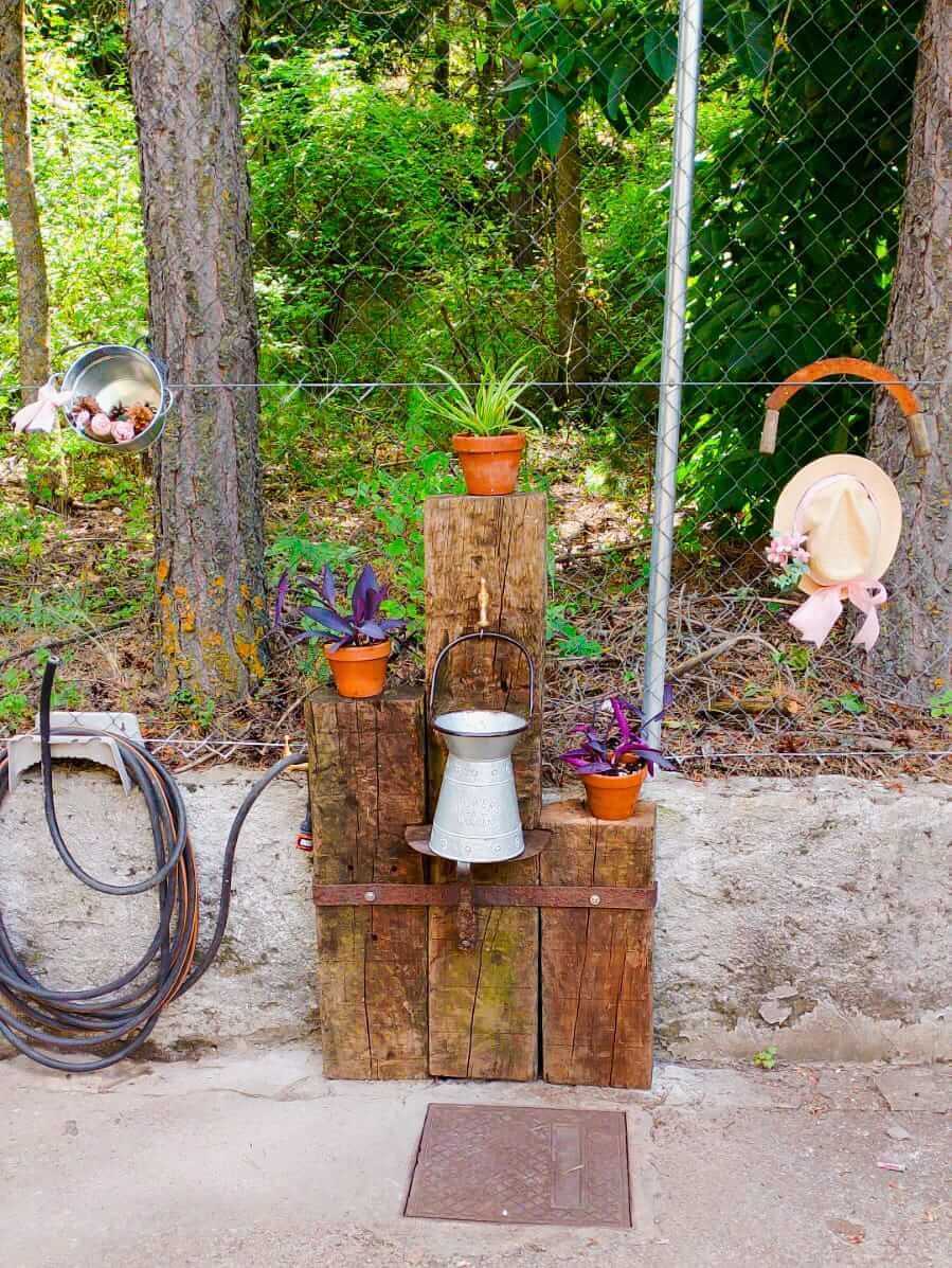 Una fuente de agua hecha con bloques de madera y plantas en macetas.