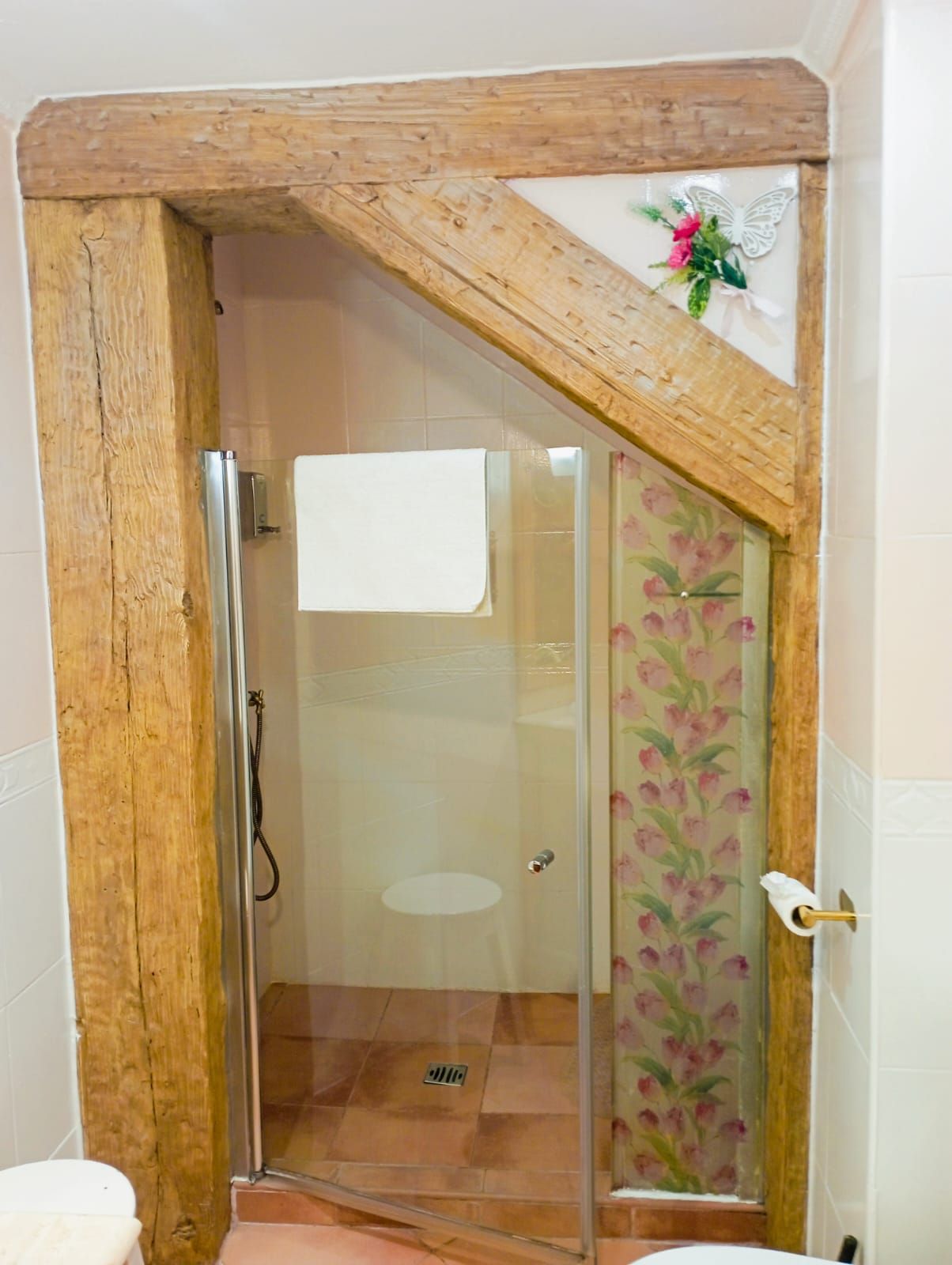 Un baño con inodoro, ducha y vigas de madera.