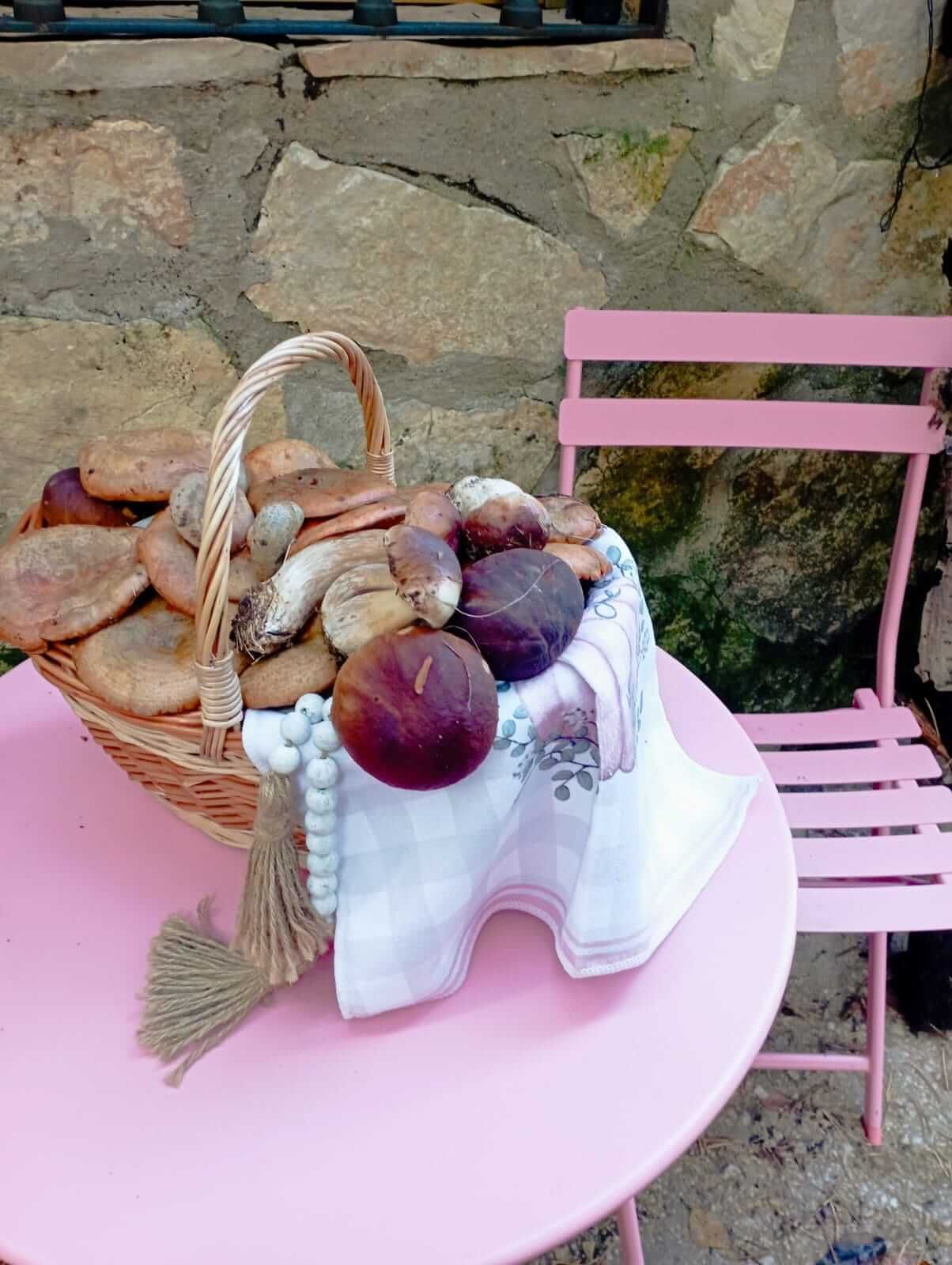 Una canasta de comida está sobre una mesa rosa al lado de una silla rosa.