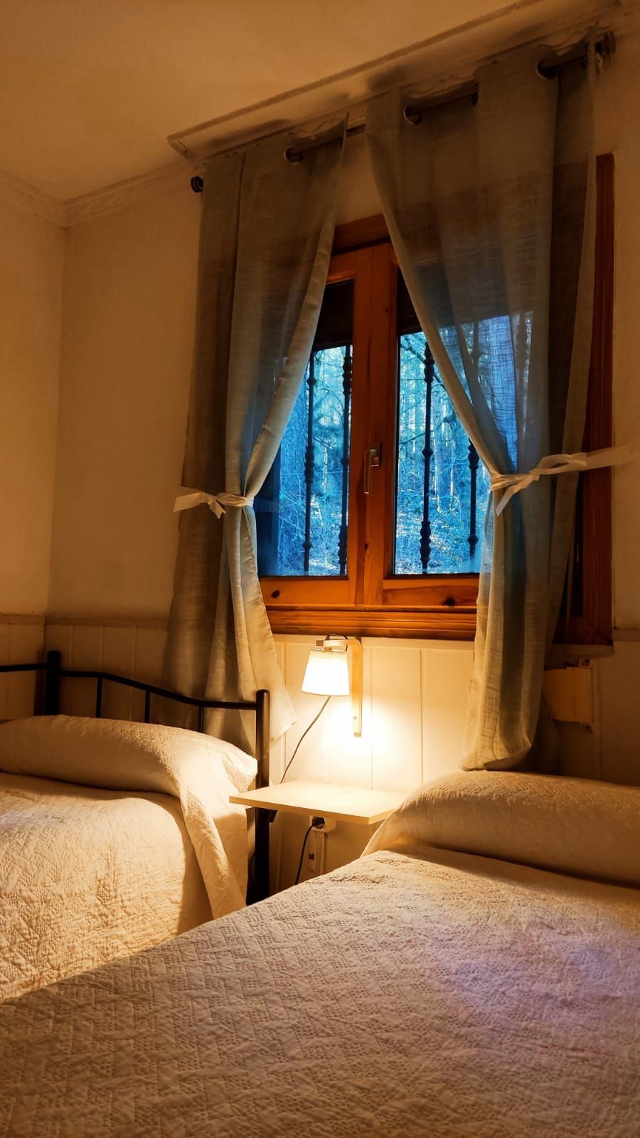 Un dormitorio con dos camas y una ventana con cortinas.