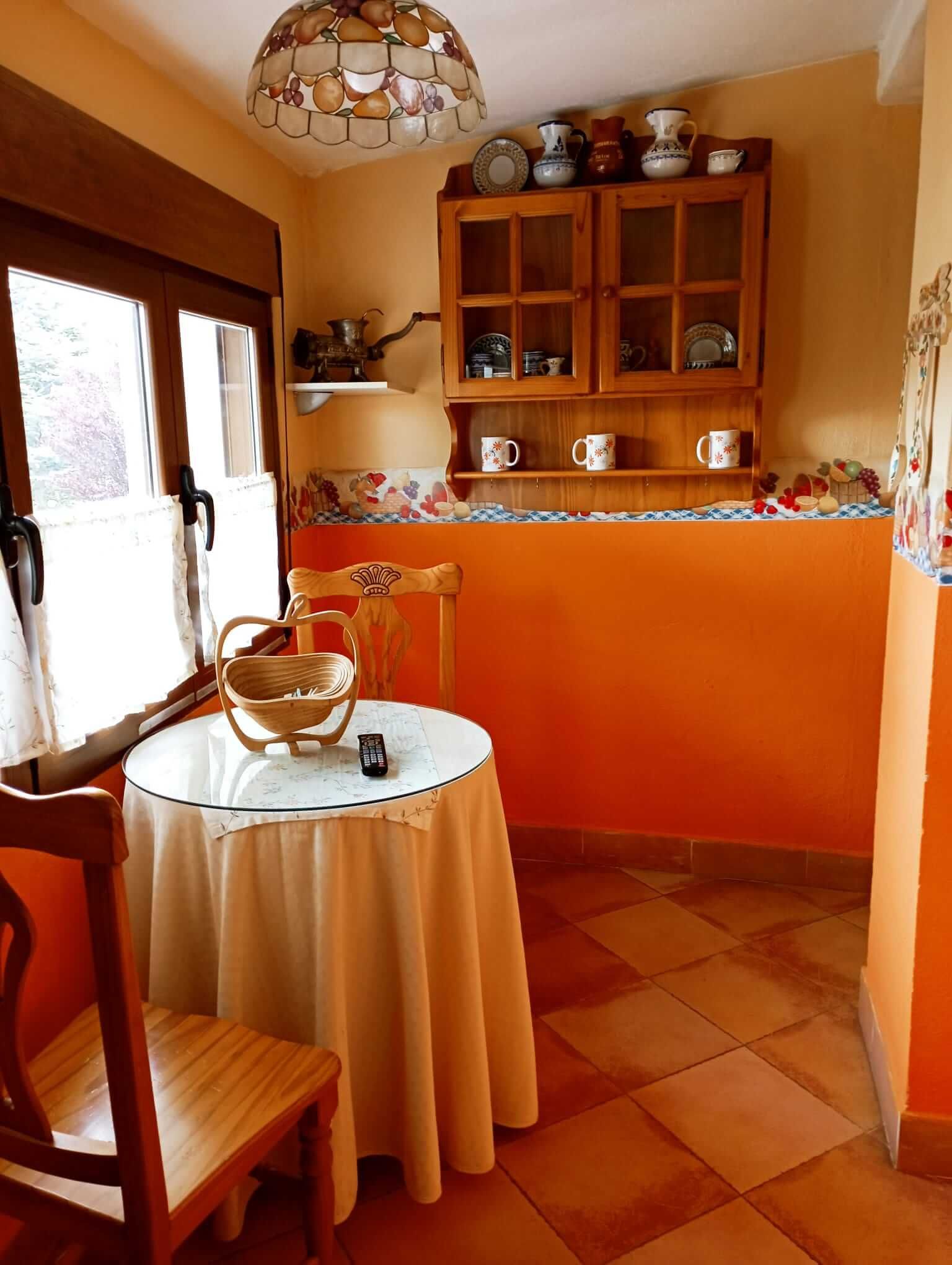 Una mesa y sillas en una habitación con paredes naranjas.