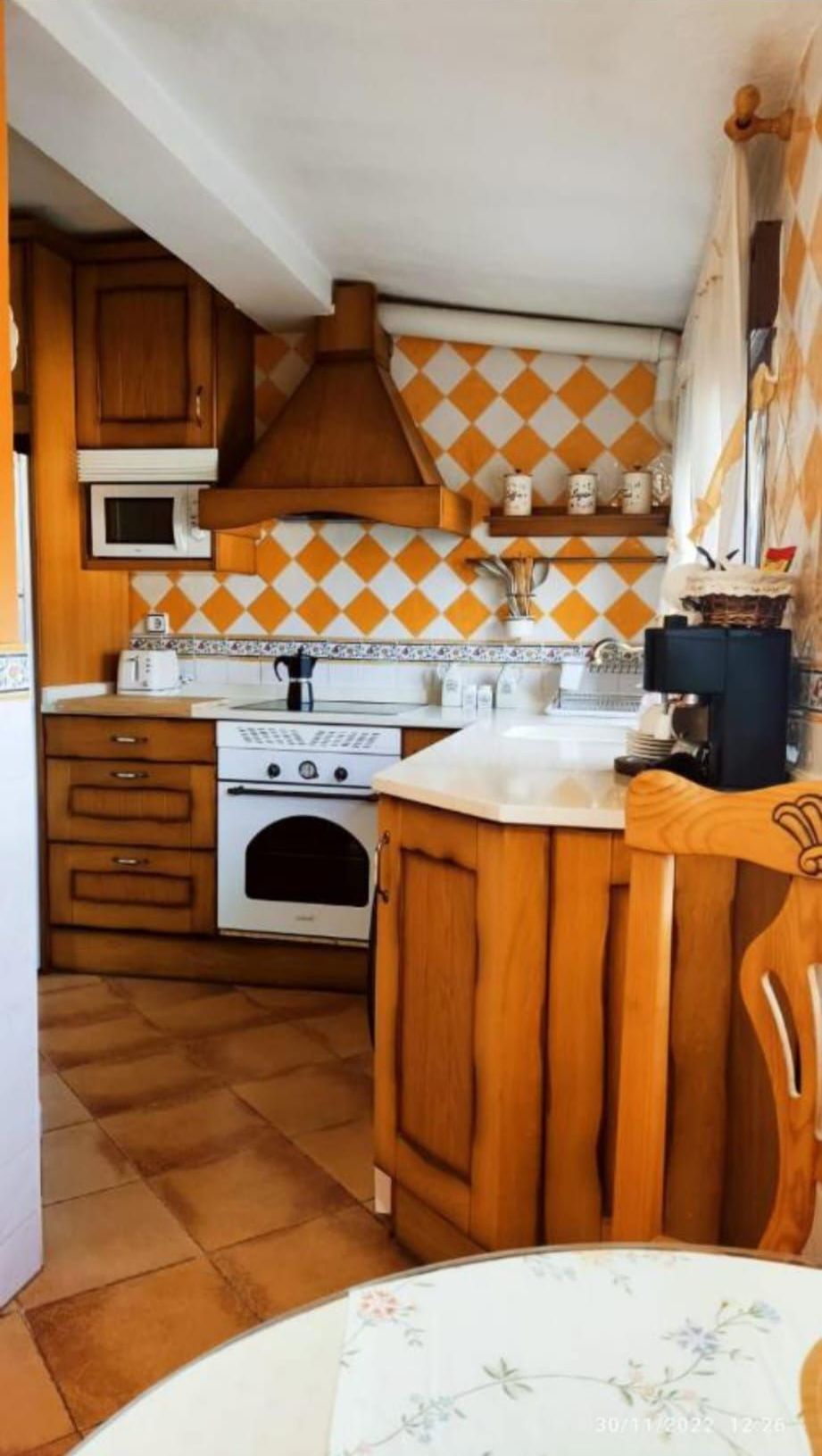 Una cocina con gabinetes de madera, una estufa, un microondas y una mesa.