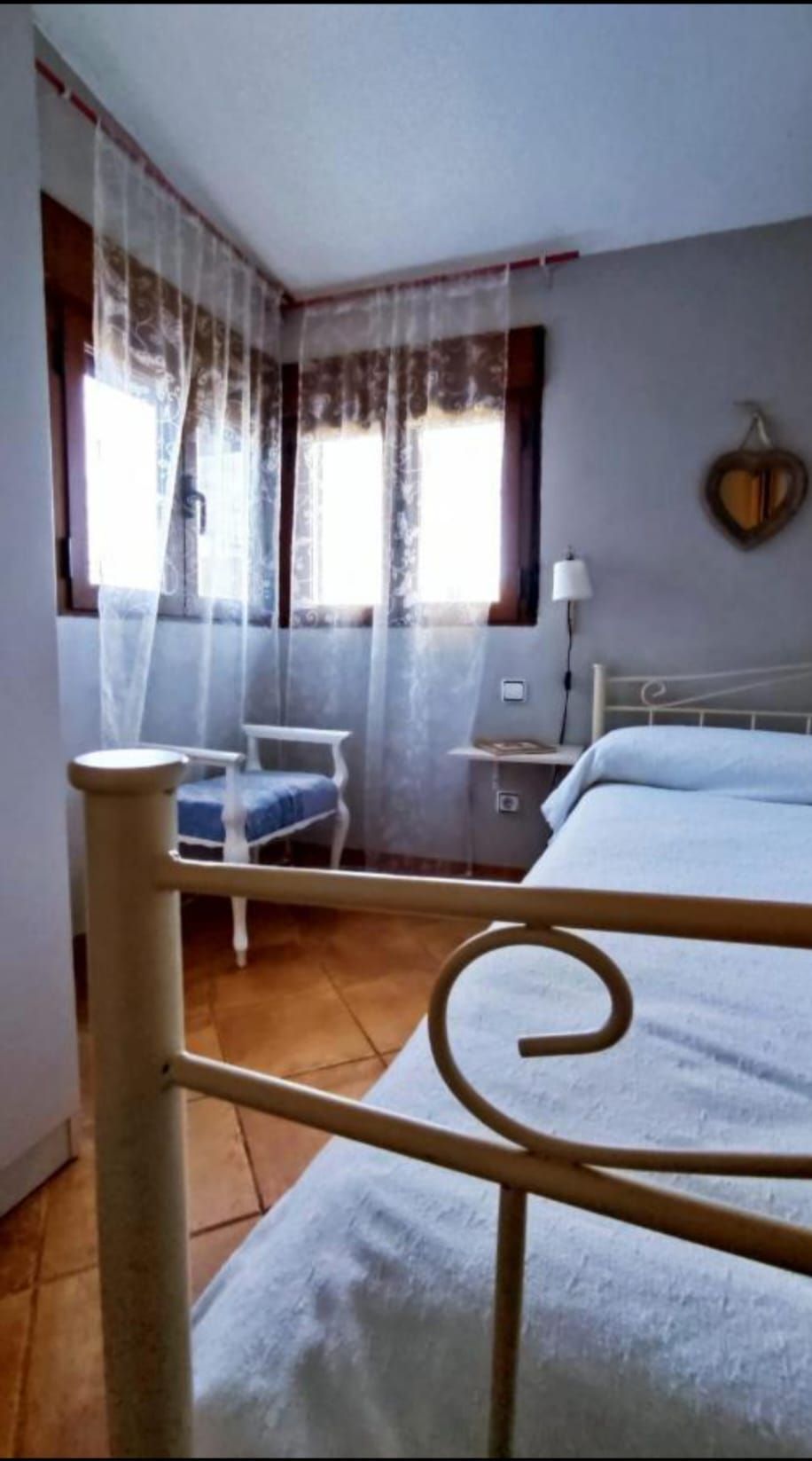 Un dormitorio con una cama, una silla y una ventana.