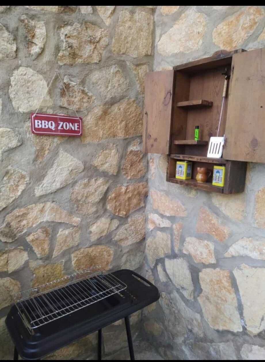 Un cartel de zona de barbacoa está colgado en una pared de piedra.