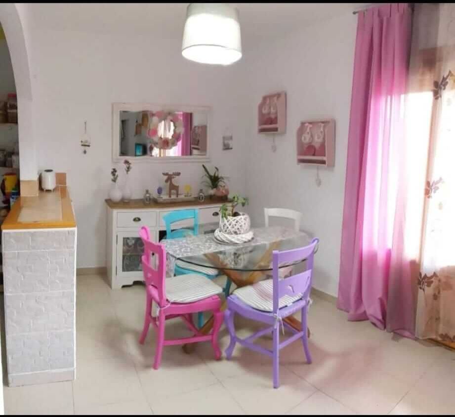 Un comedor con mesa y sillas y cortinas rosas.