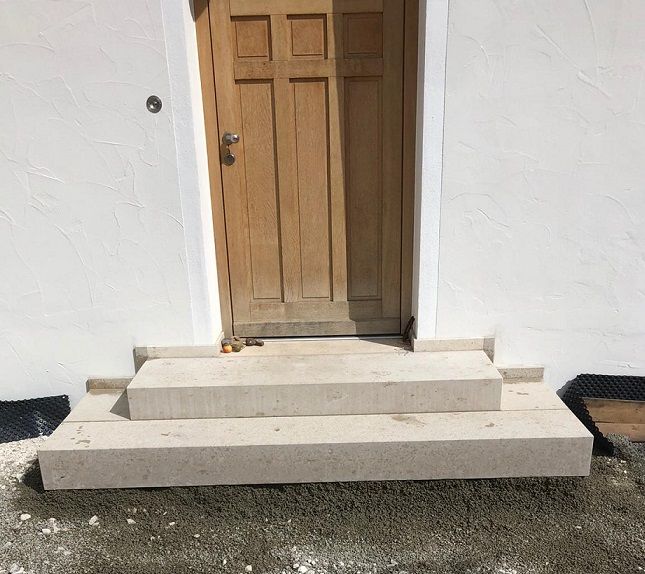 Heller Grabstein mit vier eingearbeiteten Steinen