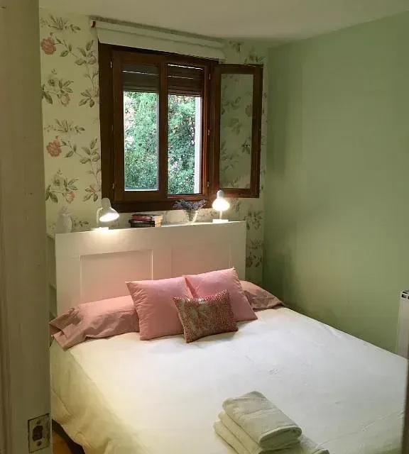 Un dormitorio con una cama blanca y almohadas rosas.