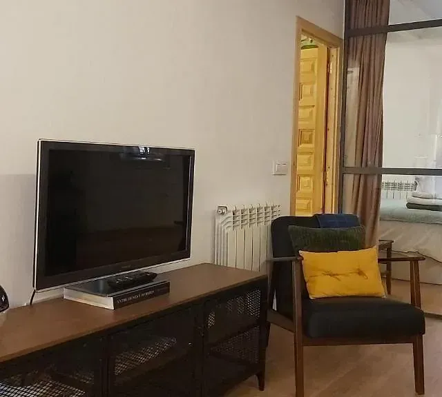 Una sala de estar con televisión, silla y radiador.
