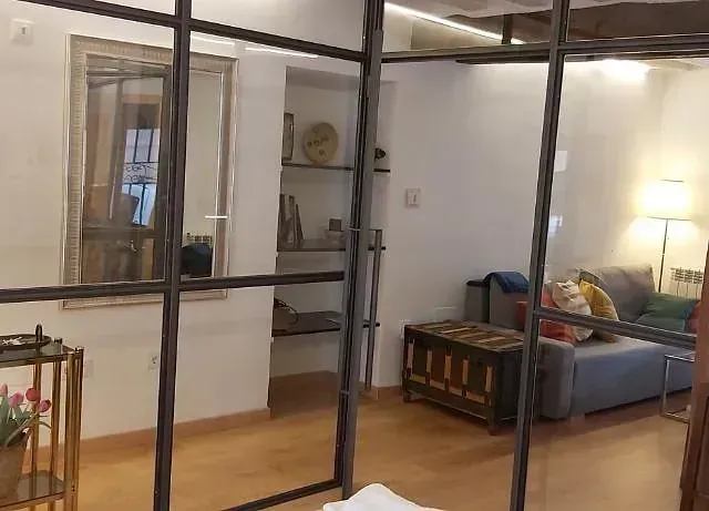 Una sala de estar con un sofá y un espejo detrás de una pared de vidrio.