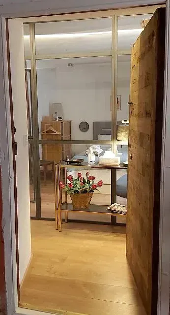 Una puerta de madera se abre a una sala de estar con una pared de vidrio.