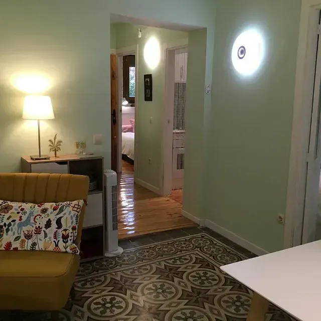 Una sala de estar con un sofá amarillo y una mesa blanca.