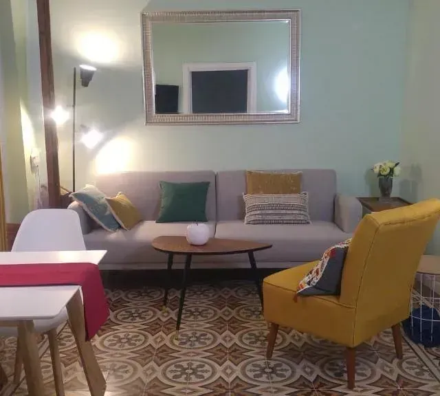 Una sala de estar con sofá, sillas, mesa y espejo.