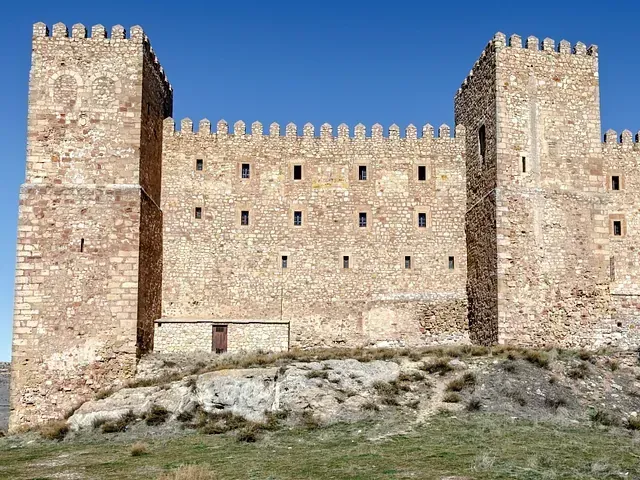 Un gran castillo de piedra está situado en la cima de una colina.