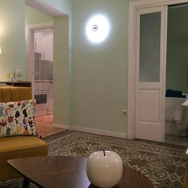 Una sala de estar con un sofá amarillo y una manzana blanca sobre una mesa.