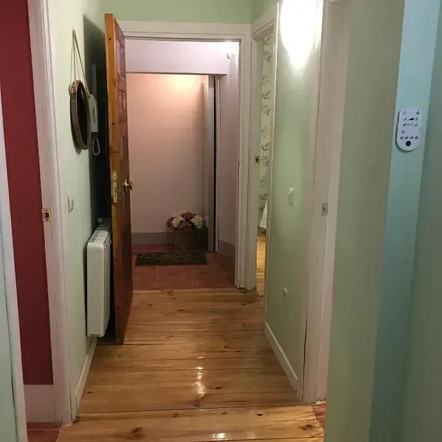 Un pasillo con suelo de madera y una puerta que conduce a una habitación.