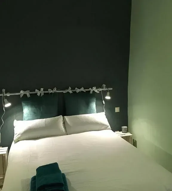 Una cama con sábanas blancas y almohadas azules en un dormitorio.