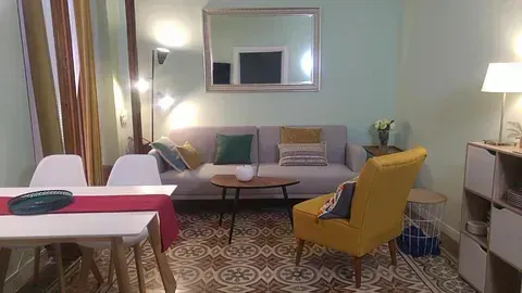 Una sala de estar con sofá, sillas, mesa y espejo.