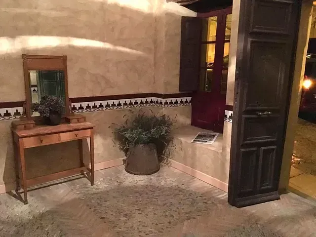 Una habitación con una mesa, un espejo y una planta en maceta.