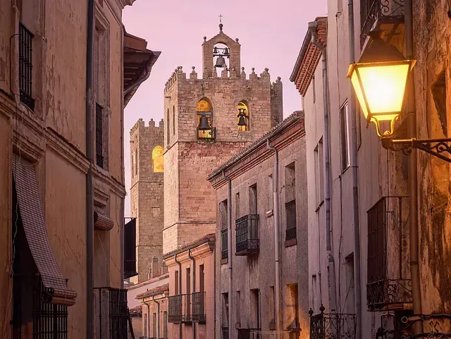 Una calle estrecha con una torre de reloj al fondo.