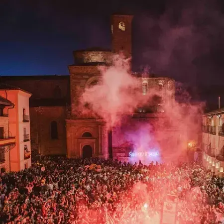 Una gran multitud de personas se reúne frente a un edificio por la noche.
