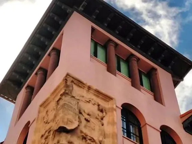 Mirando hacia arriba a un edificio rosa con columnas y arcos
