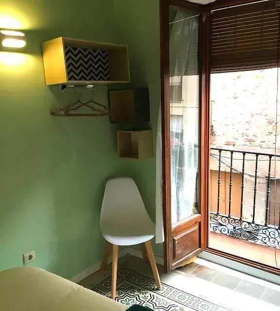 Hay una silla en la esquina de la habitación al lado de una ventana.