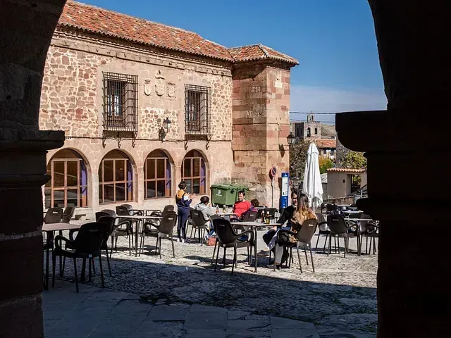 Un grupo de personas están sentadas en mesas afuera de un edificio.