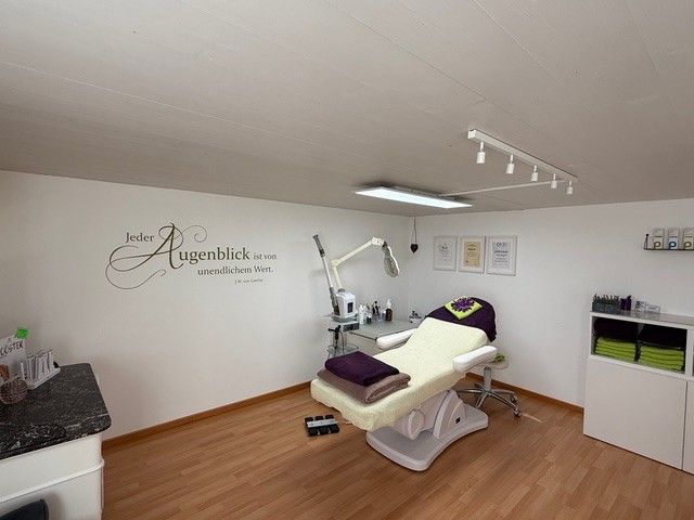 Saloninterieur mit Behandlungsliege, Beleuchtung und dekorativer Wandkunst.