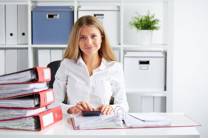 Lächelnde Geschäftsfrau berechnet Steuern am Schreibtisch im Büro