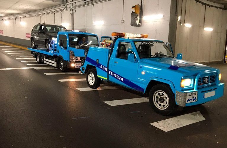 Una grúa azul está remolcando un automóvil en un estacionamiento.