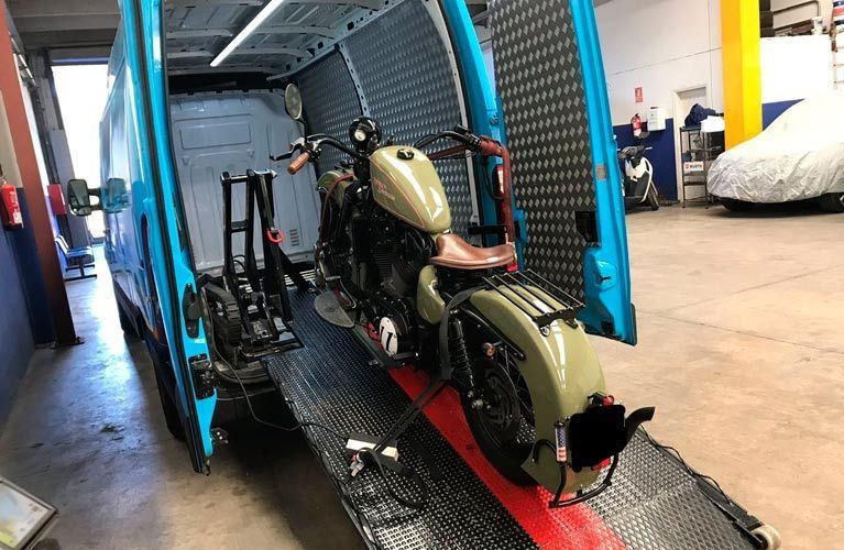 Una motocicleta está siendo remolcada por un camión en un garaje.