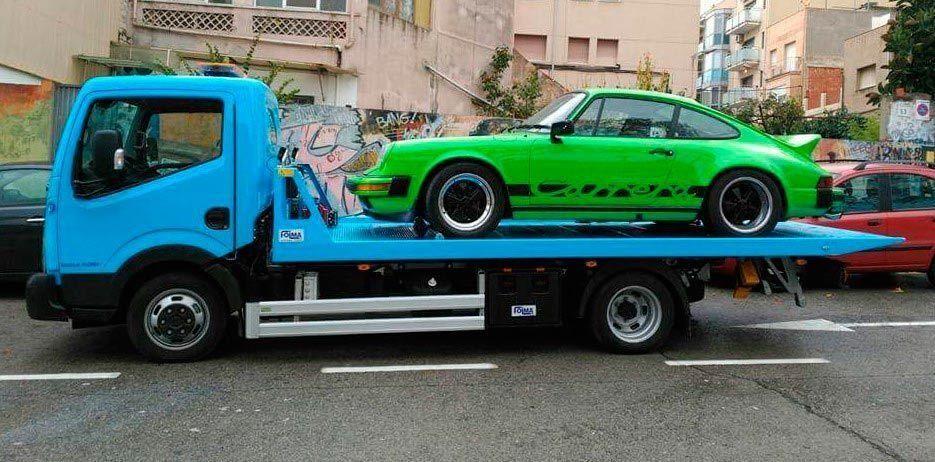 Un coche verde está encima de una grúa azul.