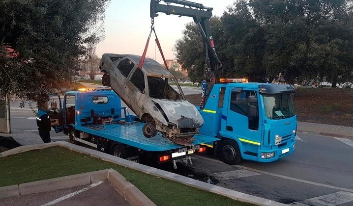 Una grúa azul lleva un coche en su parte trasera