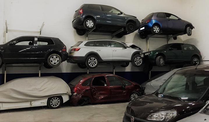 Un montón de coches están apilados uno encima del otro en un garaje.