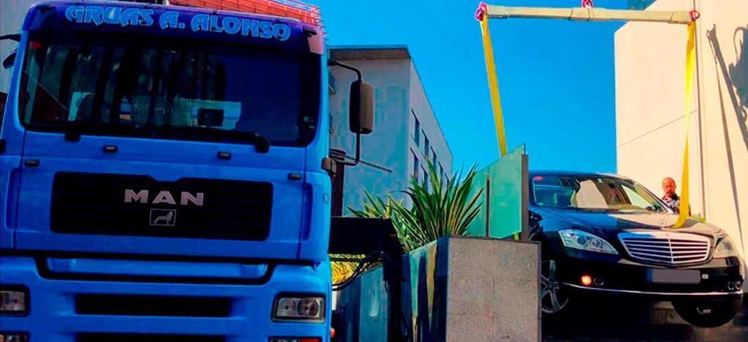 Un camión de color azul está estacionado frente a un edificio al lado de un automóvil negro.