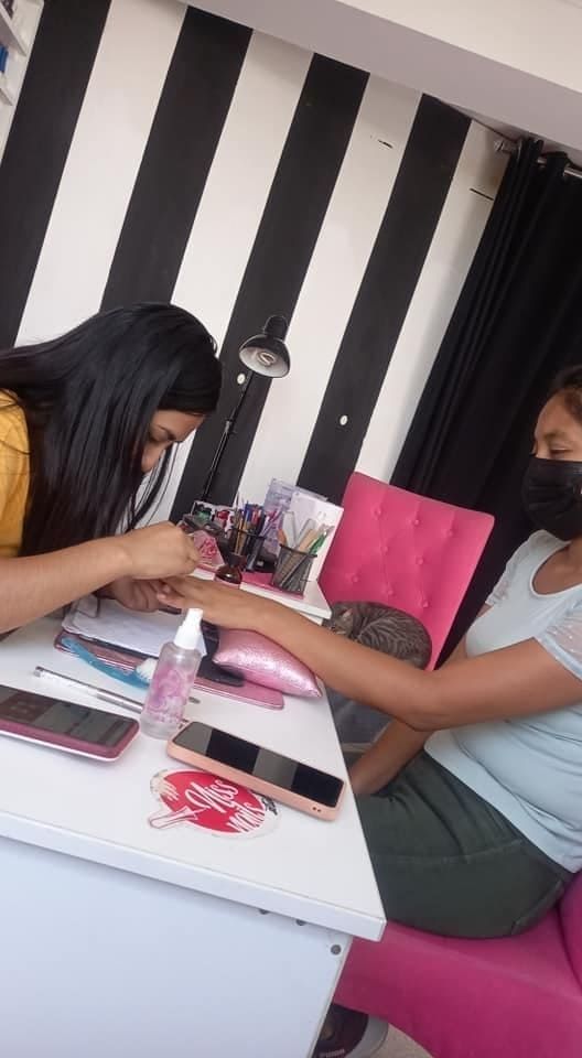 Mujer recibiendo una manicura en un salón de belleza. Pared de rayas blancas y negras.