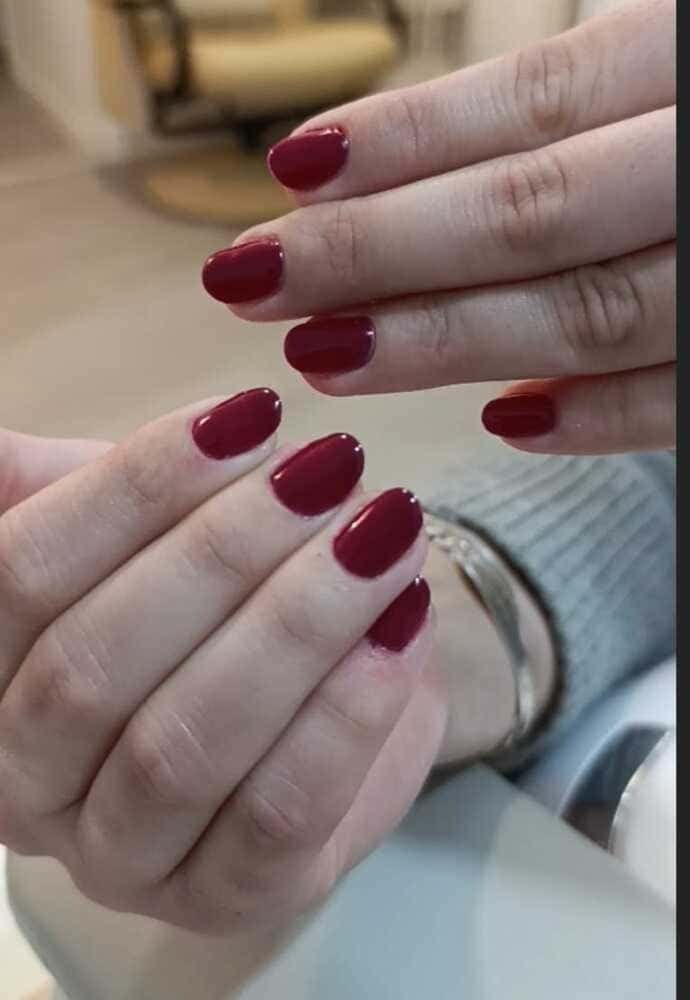 Manos con uñas de forma ovalada pintadas de un rojo intenso.