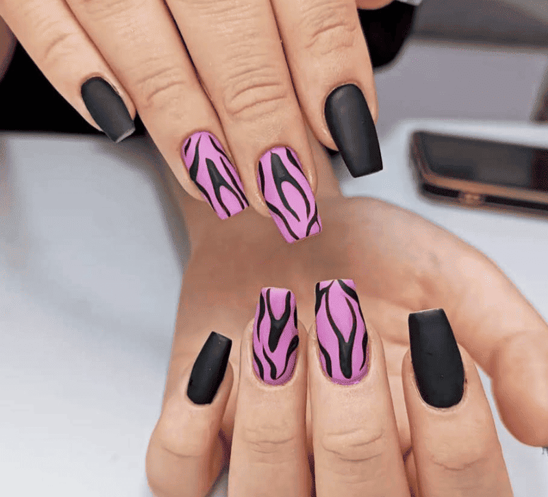 Manos con uñas con estampado de cebra en color negro mate y rosa en forma de ataúd.