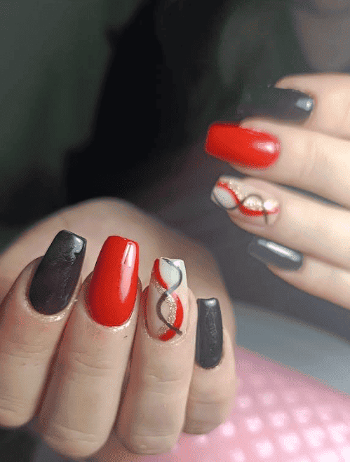 Manos con uñas largas en forma de ataúd pintadas de negro, rojo y blanco con diseños abstractos.