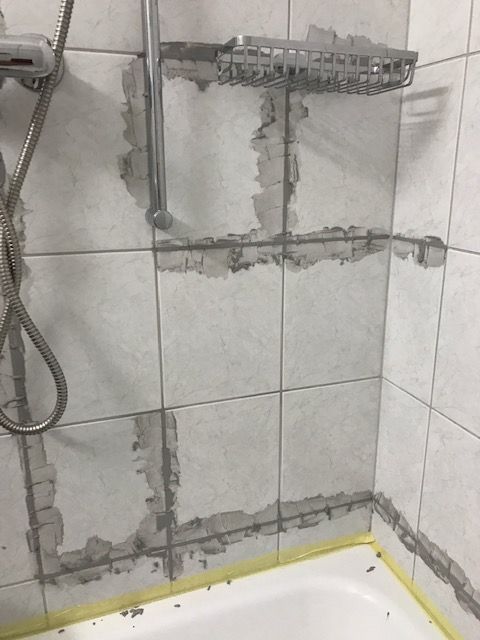 Aufgespitze Kacheln mit freigelegten Leitungen