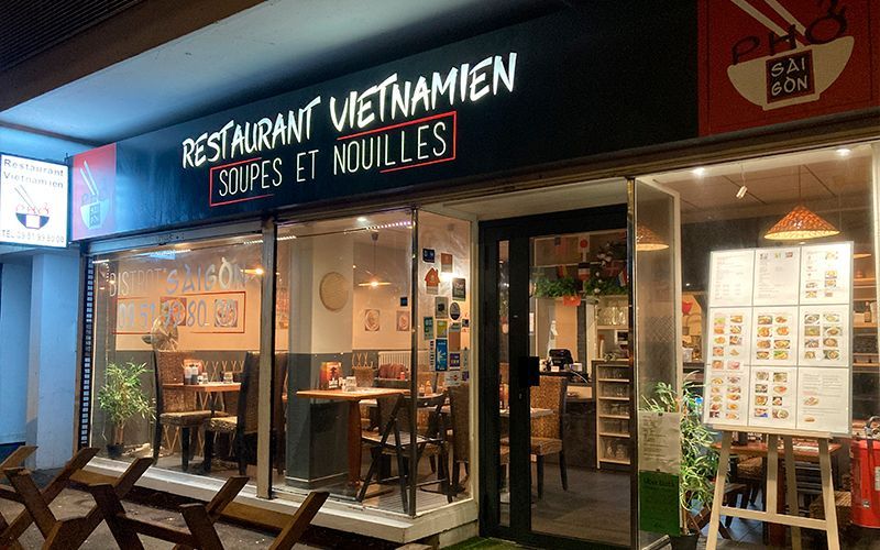 Extérieur du restaurant vietnamien Bistrot Saïgon : enseigne « Restaurant Vietnamien ». Soupes et nouilles. Vitrines, tables, plantes.