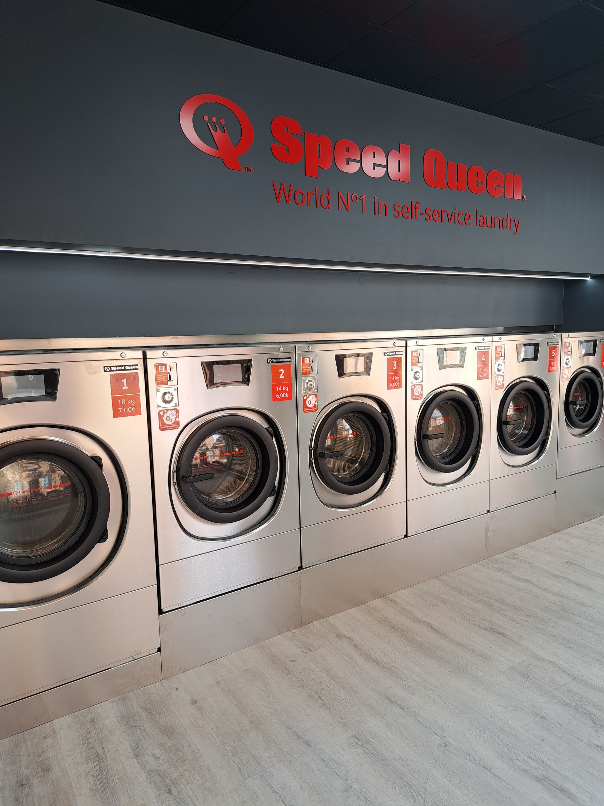 Una hilera de lavadoras Speed ​​Queen de acero inoxidable en unas instalaciones limpias y modernas.
