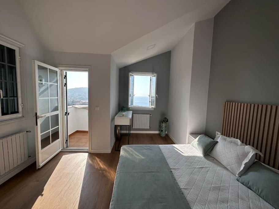 Dormitorio con cama, balcón y vista al mar. Entra la luz del sol.