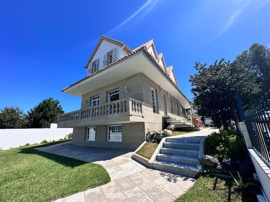 Casa de dos plantas con balcón y césped en un día soleado. Cielo azul de fondo.