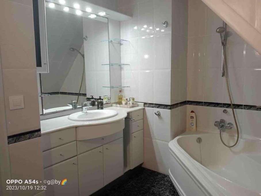 Baño blanco con lavabo, espejo, bañera y ducha.